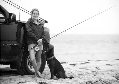Photo of a woman and her dog on the beach, holding a Thomas & Thomas saltwater fly rod